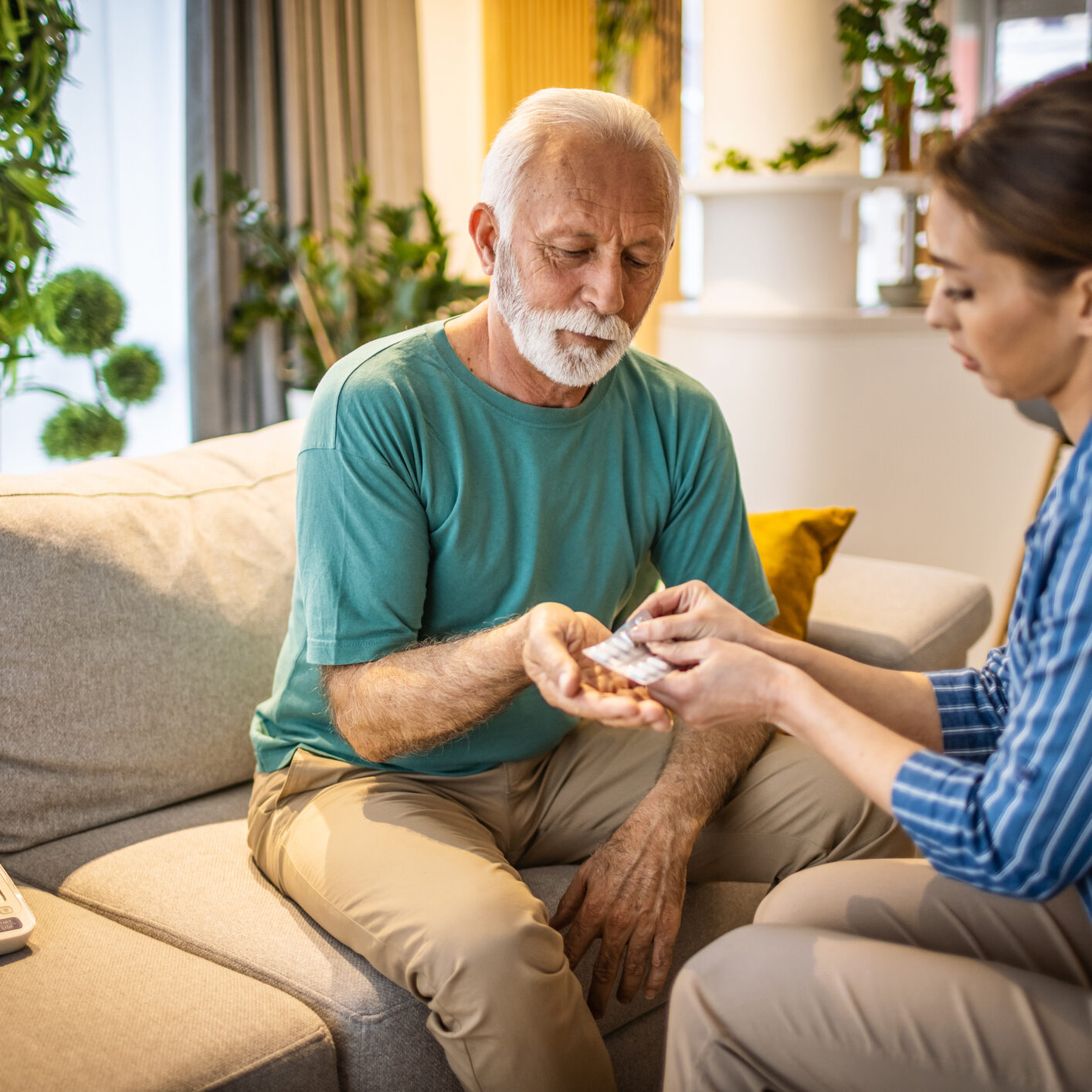 Caregiver assisting elderly man with medication