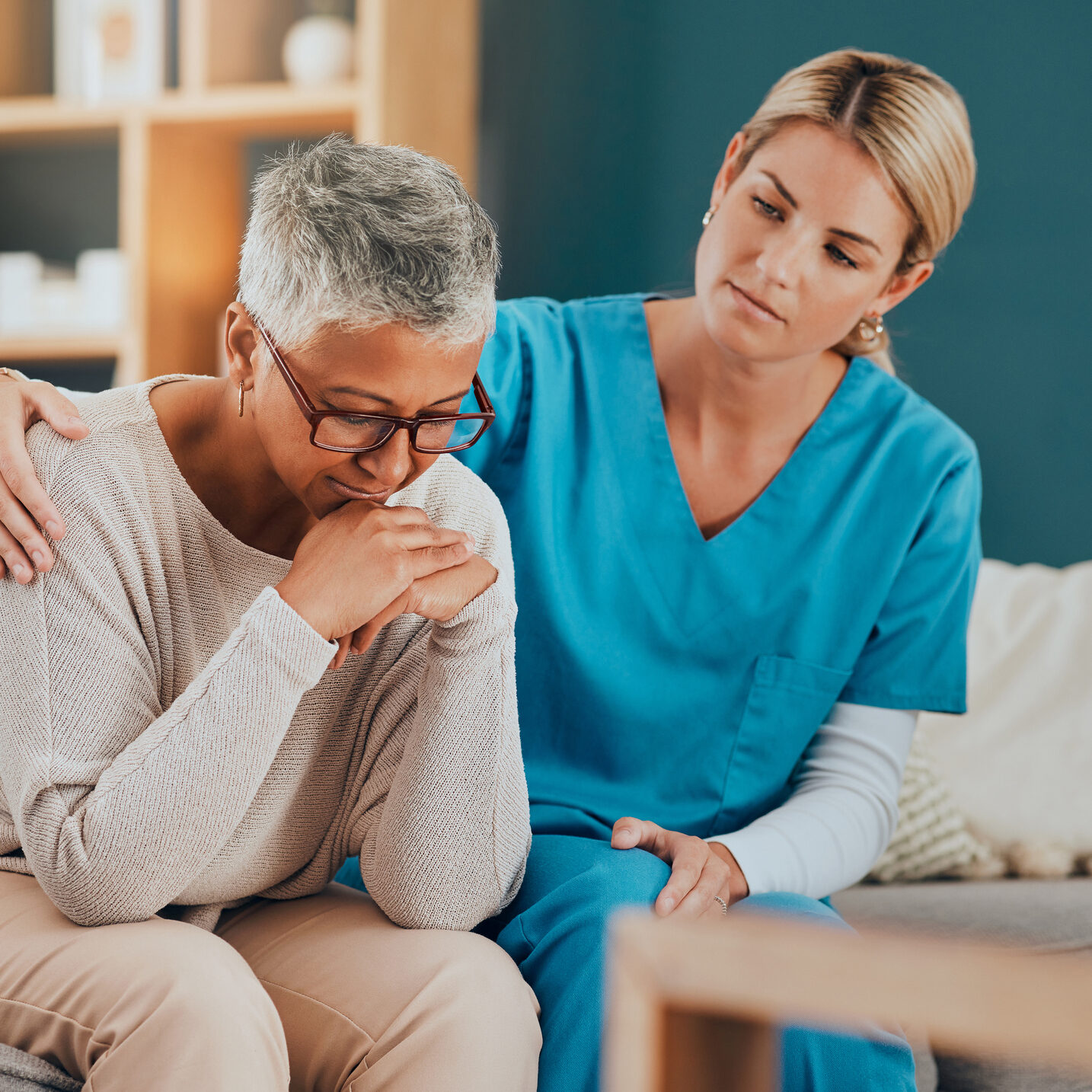 Woman comforting another on a couch