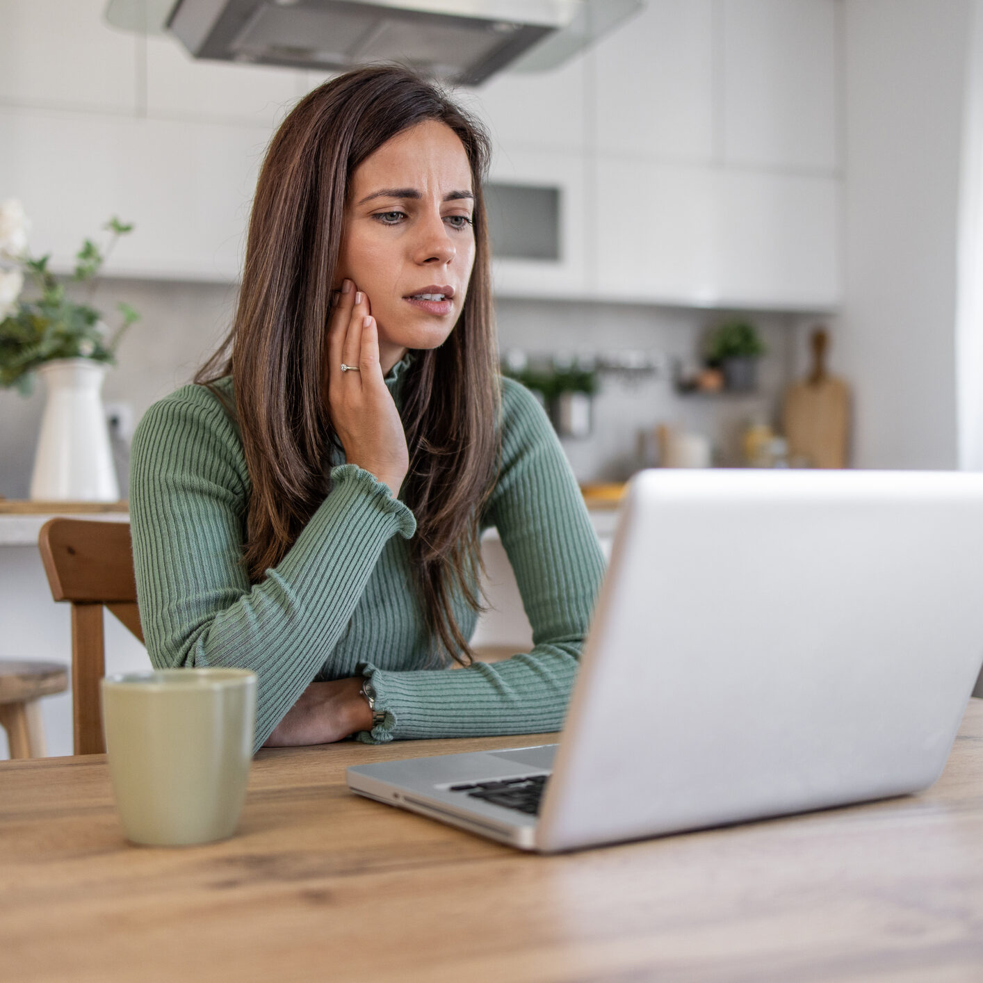 Person pondering while using a laptop